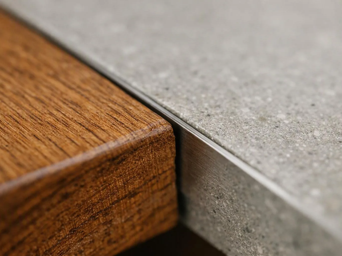 Close-up of a wooden block meeting a gray stone slab with a thin metal strip between them