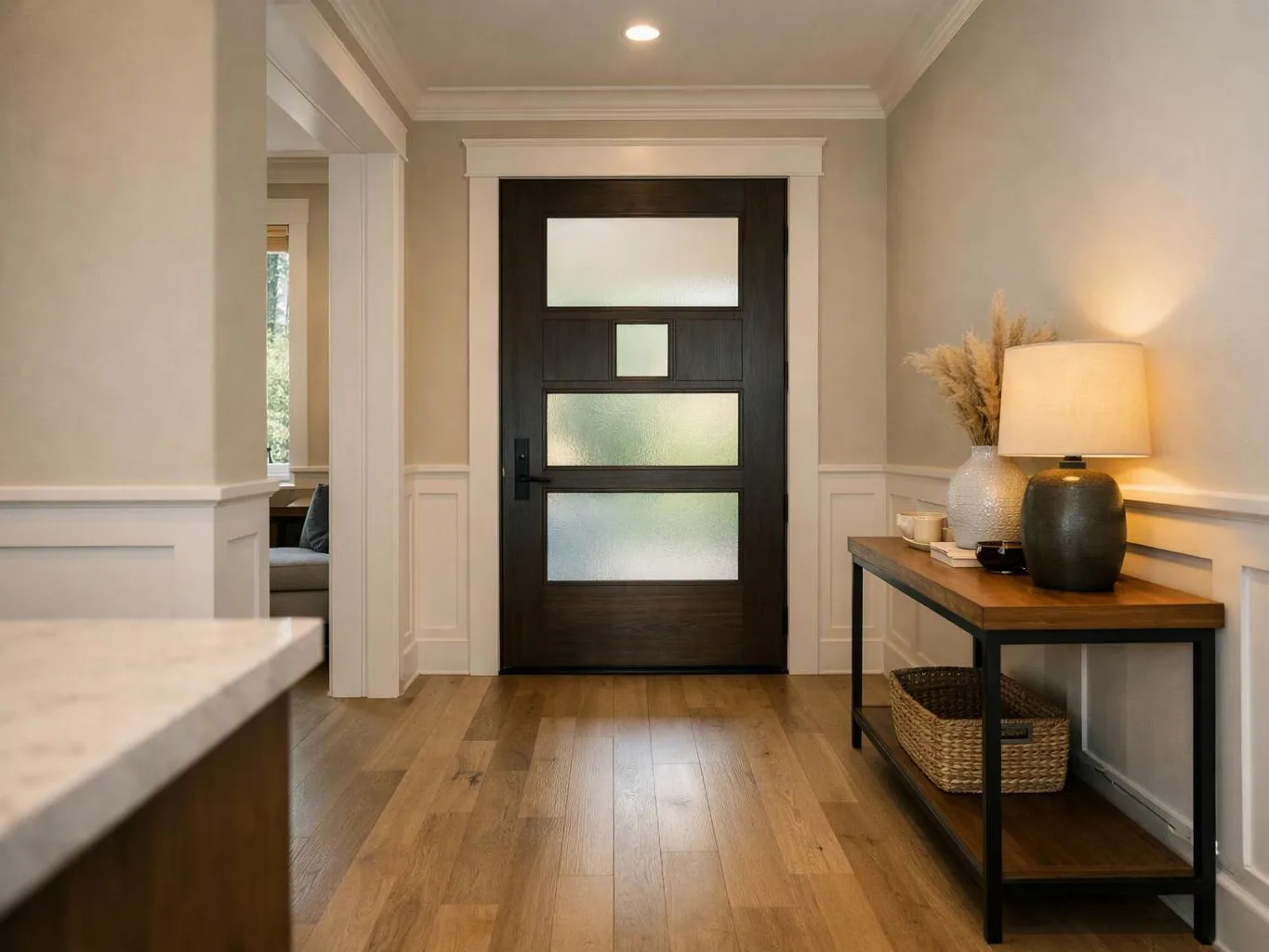 A modern entry hall shows a dark front door, wood floor, and a lamp on a console table
